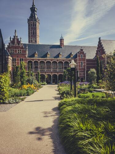Tuinpad leidt naar een historisch bakstenen gebouw met een hoge toren.