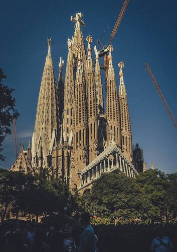 De hoge, rijk versierde torens van de Sagrada Família tegen een blauwe lucht.