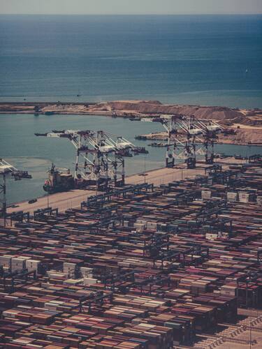 Luchtzicht op een grote containerhaven naast de blauwe zee.